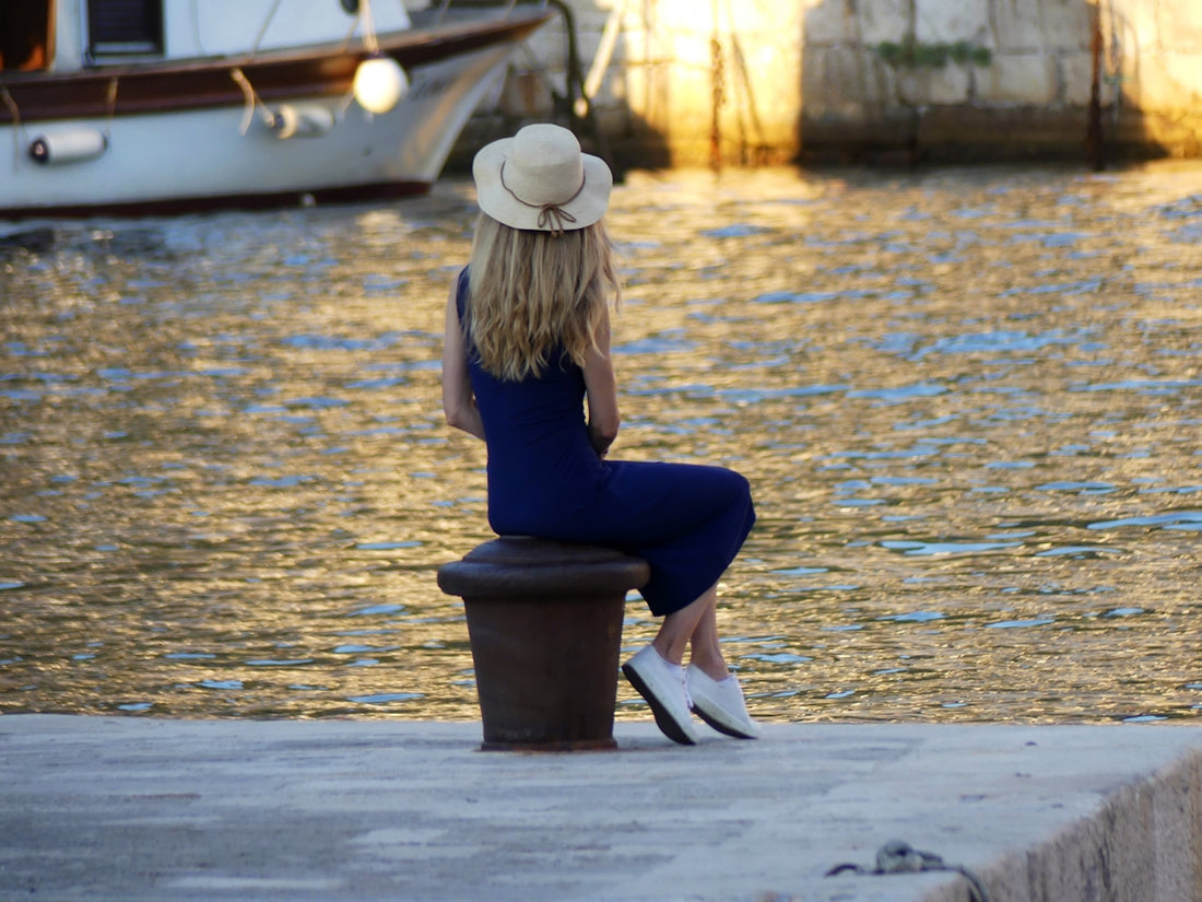 a woman sitting on a bench looking out at the water