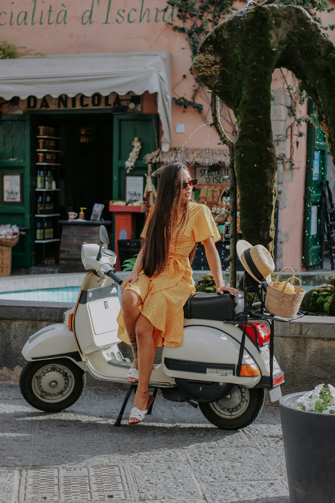 a woman in a yellow dress is sitting on a scooter