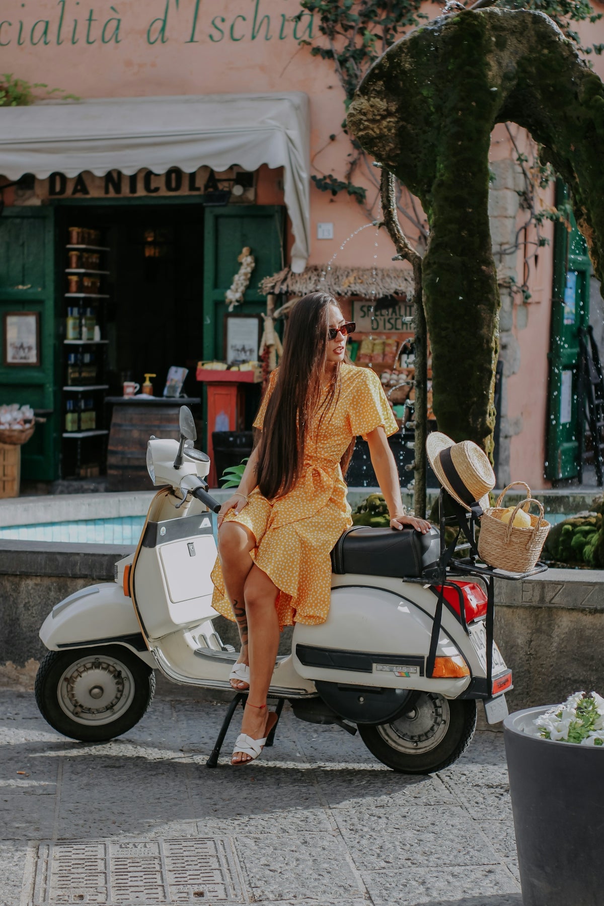 a woman in a yellow dress is sitting on a scooter