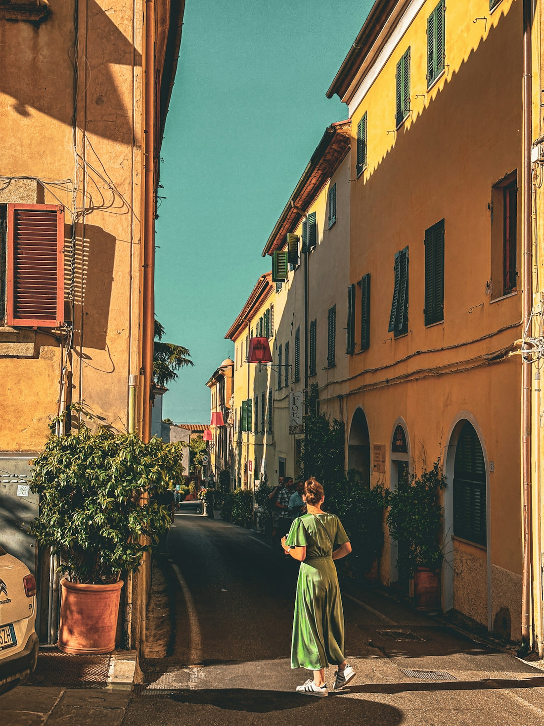 a woman in a green dress walking down a street