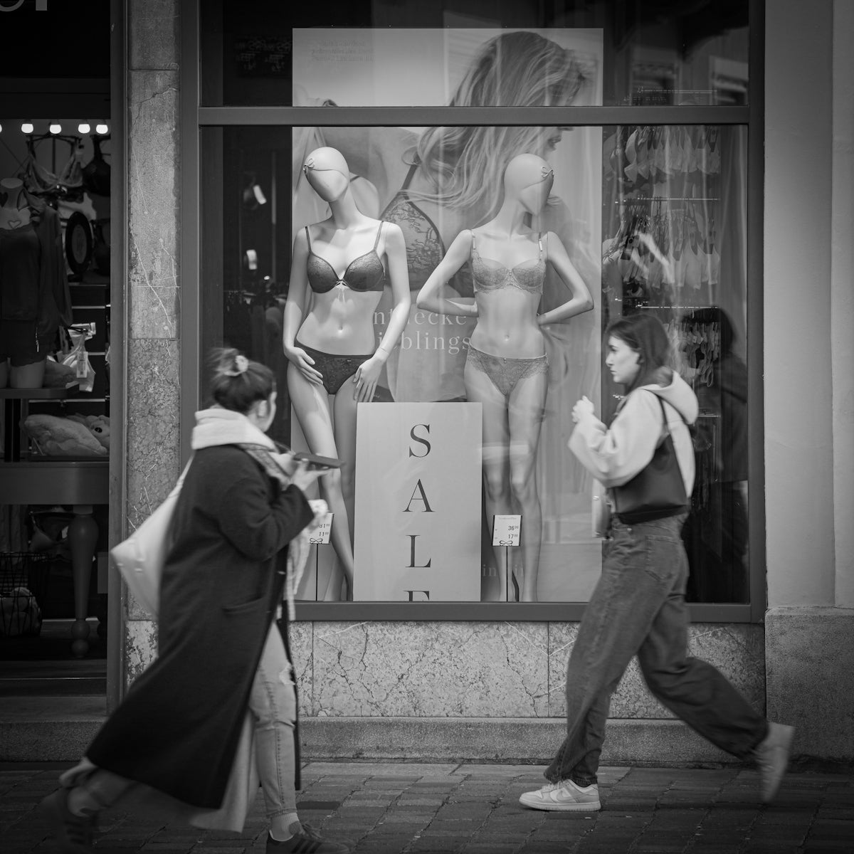 A man and a woman walking past a store window