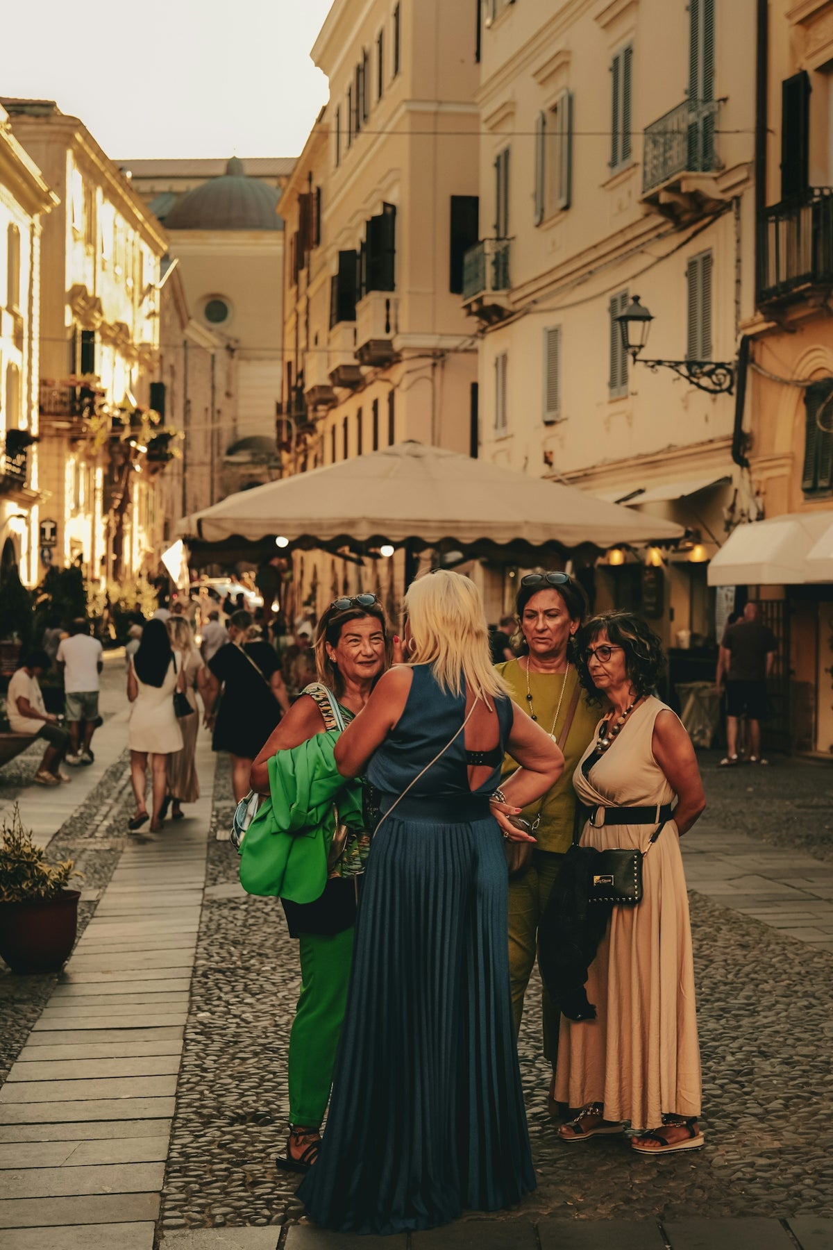 Four women talking on a cobblestone street.